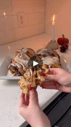 a person is holding food in their hand while standing on the kitchen counter with candles