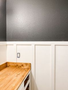 an empty room with wood counter top and white paneling