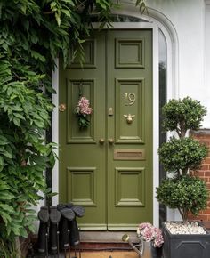 a green front door surrounded by potted plants