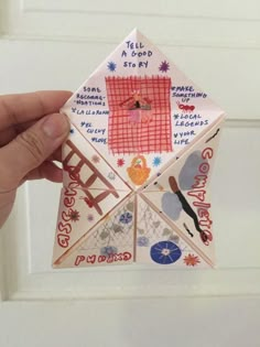 someone is holding up a folded origami piece with words and pictures on it