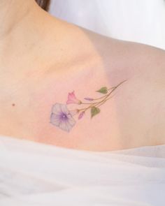 a close up of a woman's shoulder with a flower tattoo on her chest