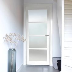 a vase filled with flowers sitting next to a white door in a room on the floor