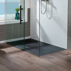 a bathroom with a walk in shower next to a bathtub and wooden flooring