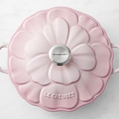 a pink flower shaped dish with the word le creuset on it's side