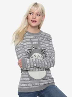 a woman with long blonde hair wearing a grey and white totoro sweater, standing in front of a white background