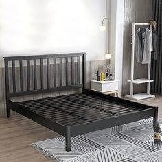 a black bed frame in a bedroom with white walls and wood flooring on the side