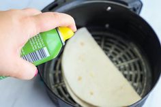 a person is using a spray bottle to put food in an air frying pan