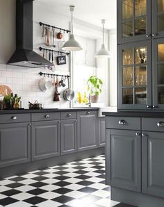 a kitchen with gray cabinets and black and white checkered flooring on the floor