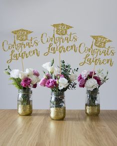 three mason jars filled with flowers on top of a wooden table