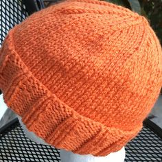 an orange knitted hat sitting on top of a white mannequin's head