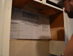 a man standing in front of a white microwave oven next to a box with papers on it