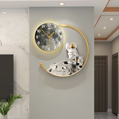 a clock with an astronaut on the moon hanging from it's side next to a plant