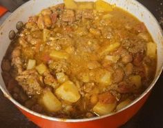 a pot filled with stew and potatoes on top of a stove next to an oven