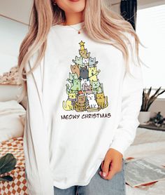 "Christmas Tree Shirt, Christmas Cat Shirt, Meowy Christmas Shirt, Christmas Cat Shirt, Retro Christmas Shirt, Merry Christmas Shirt 2023  Hi! Welcome to ThamDessignLTD.  We're thrilled to have you here!  At ThamDessignLTD, we offer a range of clean, high-quality, and soft shirts. Each item is carefully prepared by our boutique and undergoes thorough ironing before being shipped to you. We want you to have a seamless shopping experience and enjoy browsing through our collection. If you have any questions or need assistance, please don't hesitate to reach out to us. We're here to help you at any time. To ensure the perfect fit, we kindly request you to check our size cards before making your purchase. It will help you find the right size and ensure that you're completely satisfied with your White Cat Print Top For Winter, White Long Sleeve T-shirt With Cat Design, White Cat Design Top For Winter, Winter Cotton Top With Cat Print, White Winter Top With Cat Design, Christmas Long Sleeve Tops With Cartoon Print, White Christmas Tops With Cartoon Print, White Christmas Cartoon Print Tops, White Tops With Cartoon Print For Christmas