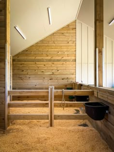 the inside of a barn with wooden walls and stalls for horses to stand up in