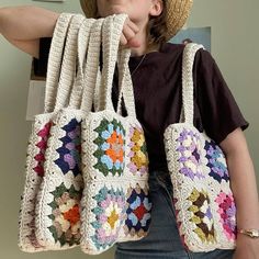 a woman wearing a straw hat holding four crocheted purses in front of her face