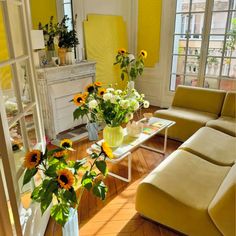 a living room with sunflowers and other flowers in vases on the coffee table