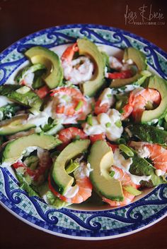 a blue and white plate topped with shrimp, avocado and lettuce