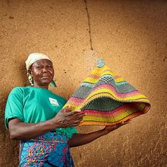 a woman holding a piece of cloth in front of a brown wall with a smile on her face