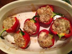 several stuffed red peppers in a white dish