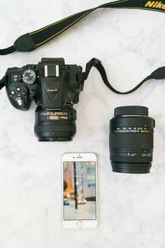 a camera, cell phone and lens sitting on a marble counter top next to each other