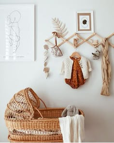 a baby's clothes hanging on the wall next to a basket