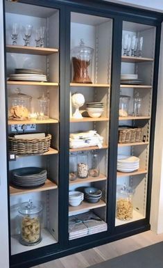 an open cabinet with glass doors and shelves filled with dishes