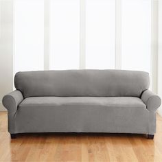 a gray couch sitting on top of a hard wood floor next to a white wall