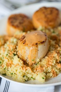 sea scallops on top of couscous in a white bowl