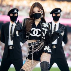 a group of women in black outfits and face masks performing on stage at a sporting event