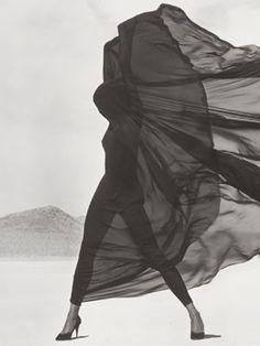 a black and white photo of a woman in high heels with her dress blowing in the wind