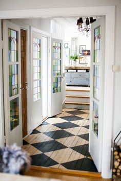 an open door leading into a hallway with stained glass panels on the walls and wood flooring