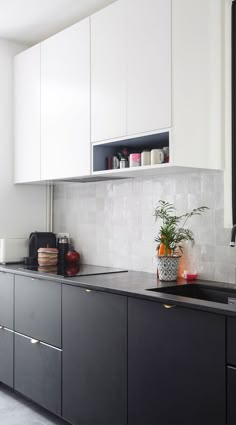 a black and white kitchen with lots of counter space on the side, along with a large mirror over the sink