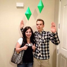 a man and woman standing next to each other in front of a wall with green kites on it