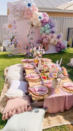 a table set up for a baby shower party with balloons and flowers on the wall