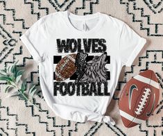 a white shirt with the words wolves football on it next to an american football ball