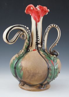 an ornate vase with a red flower on it