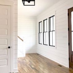 an empty room with white walls and wood floors, two doors open to the other side