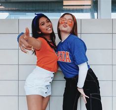 two young women posing for a photo with their arms around each other and pointing at the camera