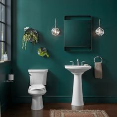 a bathroom with green walls, white fixtures and a rug in front of the toilet