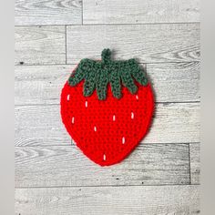 a red knitted strawberry sitting on top of a wooden floor