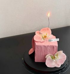 a pink cake decorated with flowers and a candle