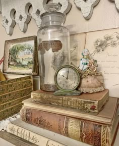 there is a clock and some books on top of each other in front of the wall