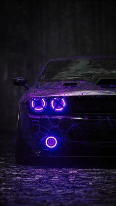 a car with purple lights on it's headlight and hood in the dark