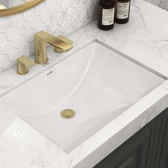 a bathroom sink with gold faucet and white marble counter top next to a mirror