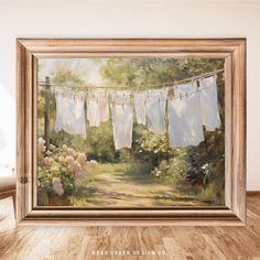 an oil painting of clothes hanging on a line over a dirt road with flowers and bushes