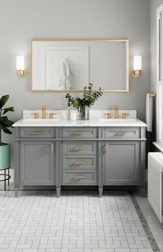 a large bathroom with two sinks and gold trimmings on the mirror above it