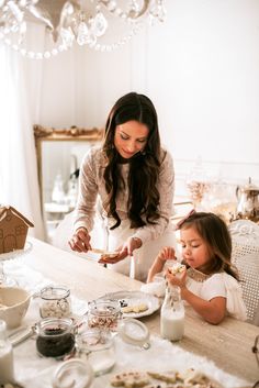 a mother and daughter sitting at a table eating cookies