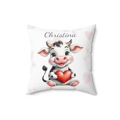 a white pillow with a cartoon cow holding a heart