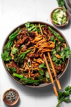 a bowl filled with noodles and vegetables next to some chopsticks on the side